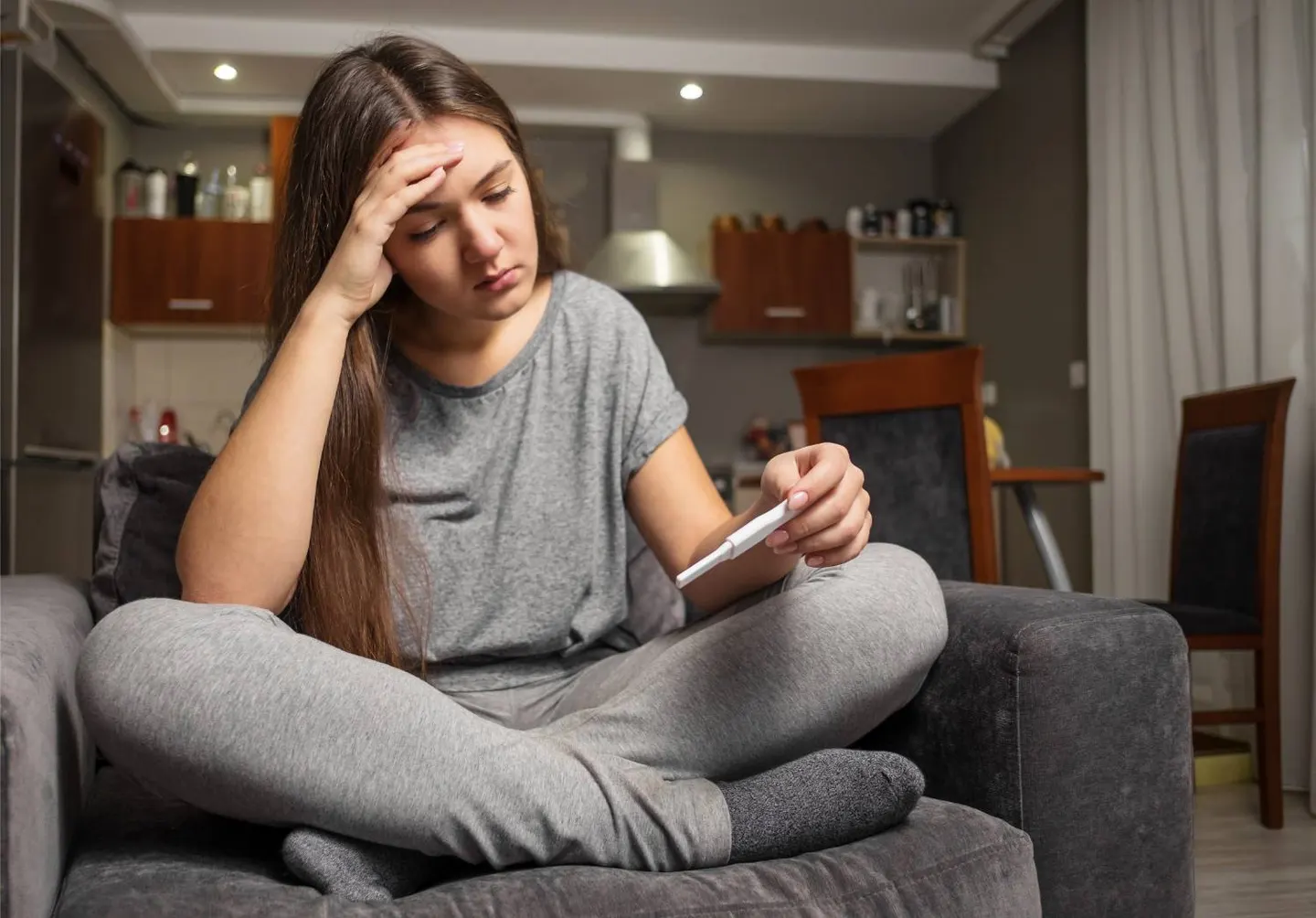 A worried young woman sitting on a couch looking at her phone