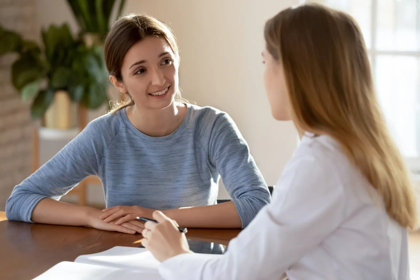 A young woman smiling while talking with a staff member at a table