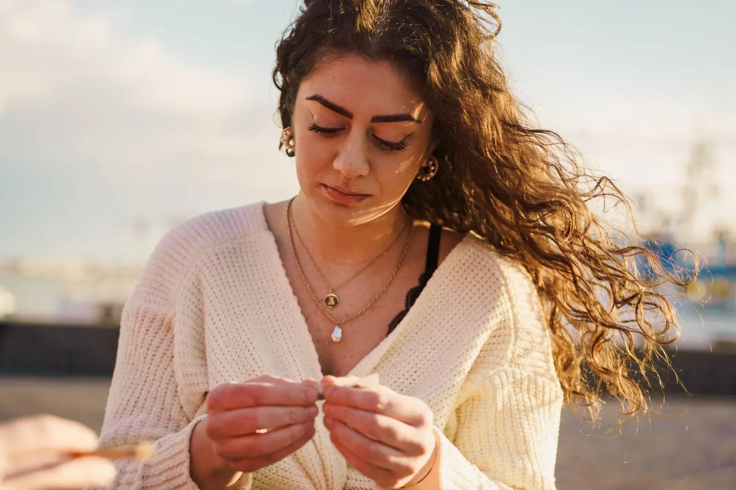 A young woman in warm evening light, looking down thoughtfully