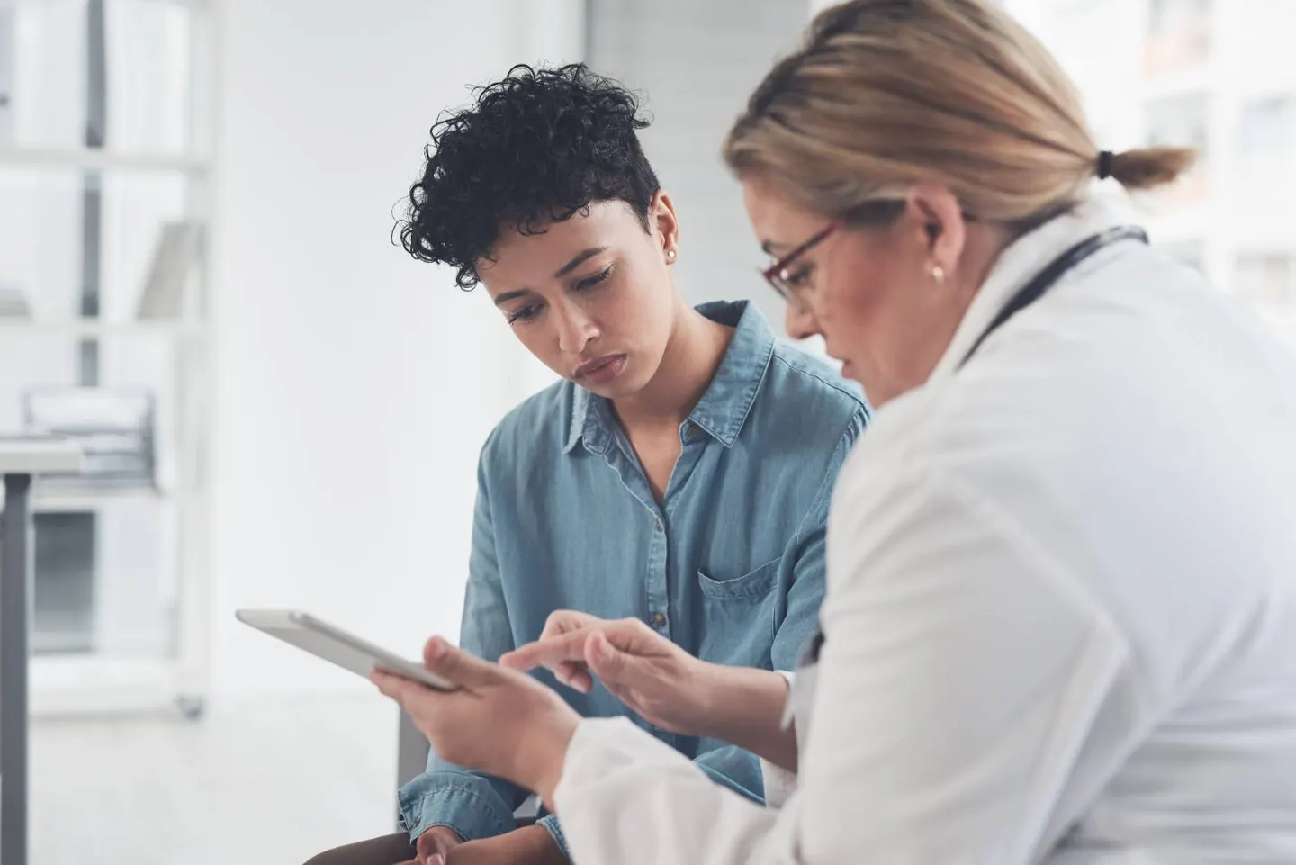 A doctor reviewing information on a tablet with a young patient