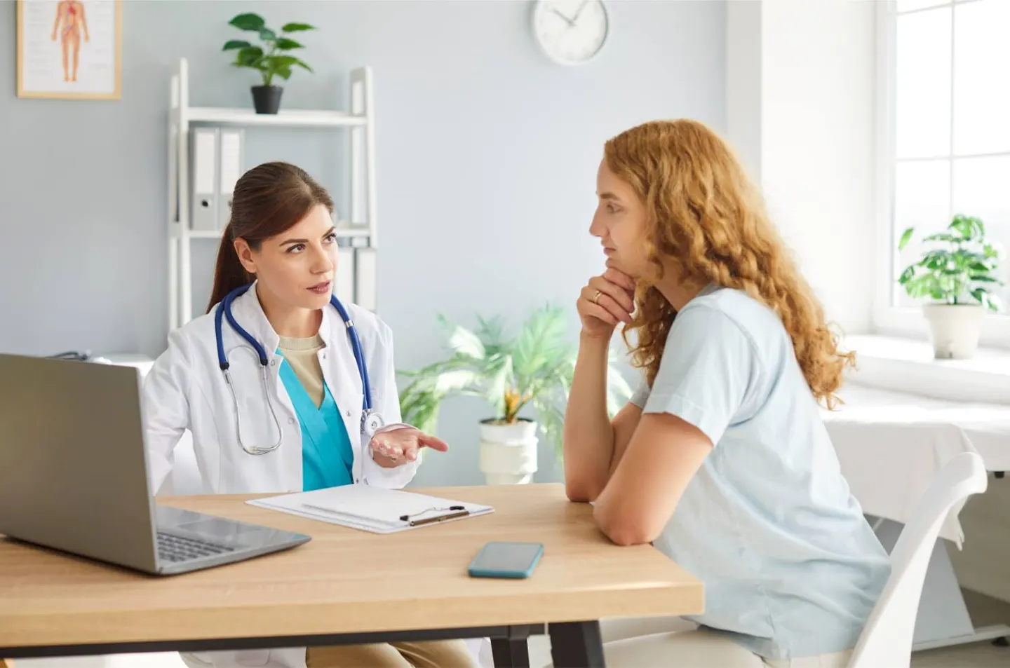 A clinician talking with a young woman across a table