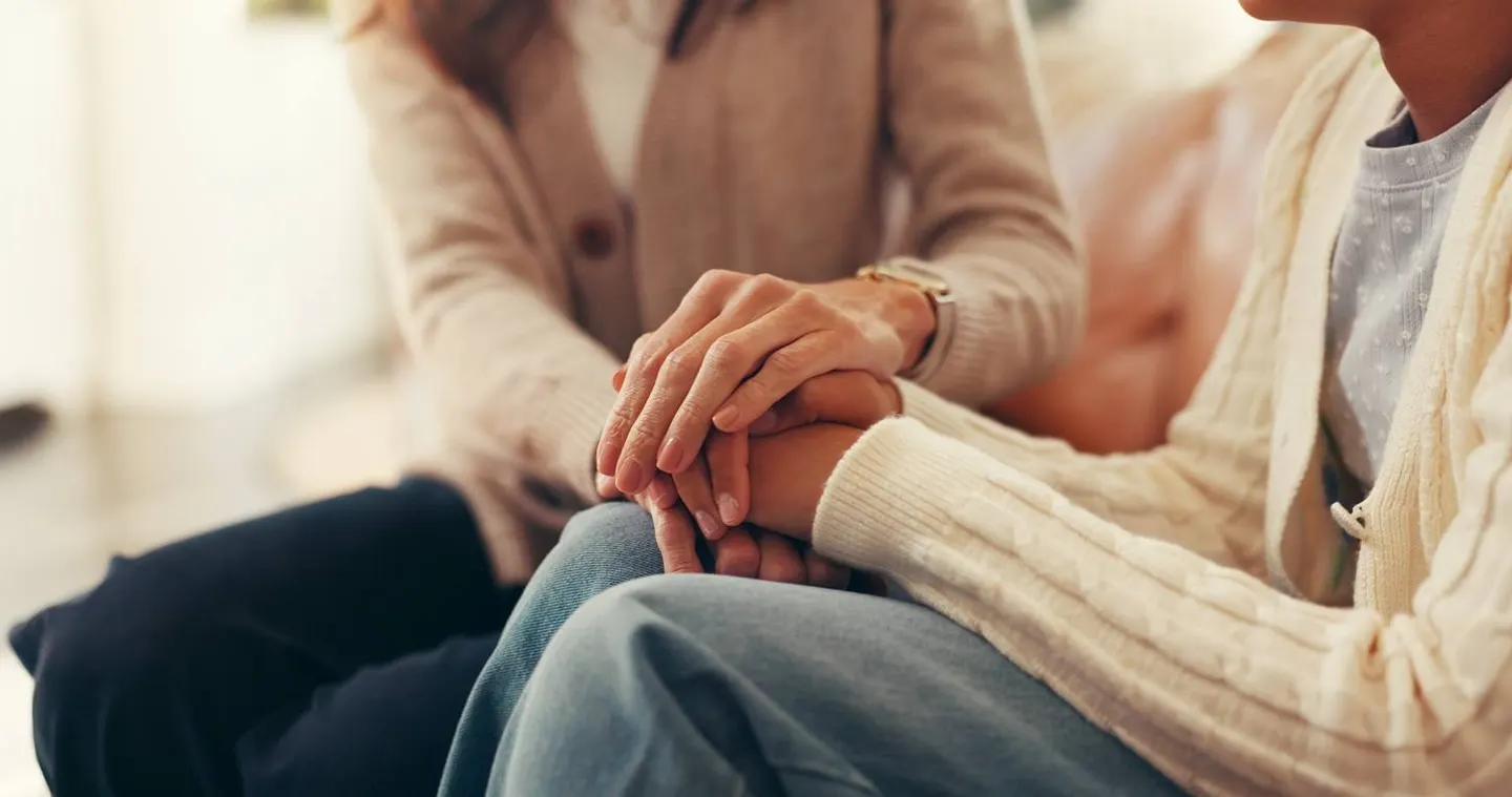 Two people holding hands in a moment of support