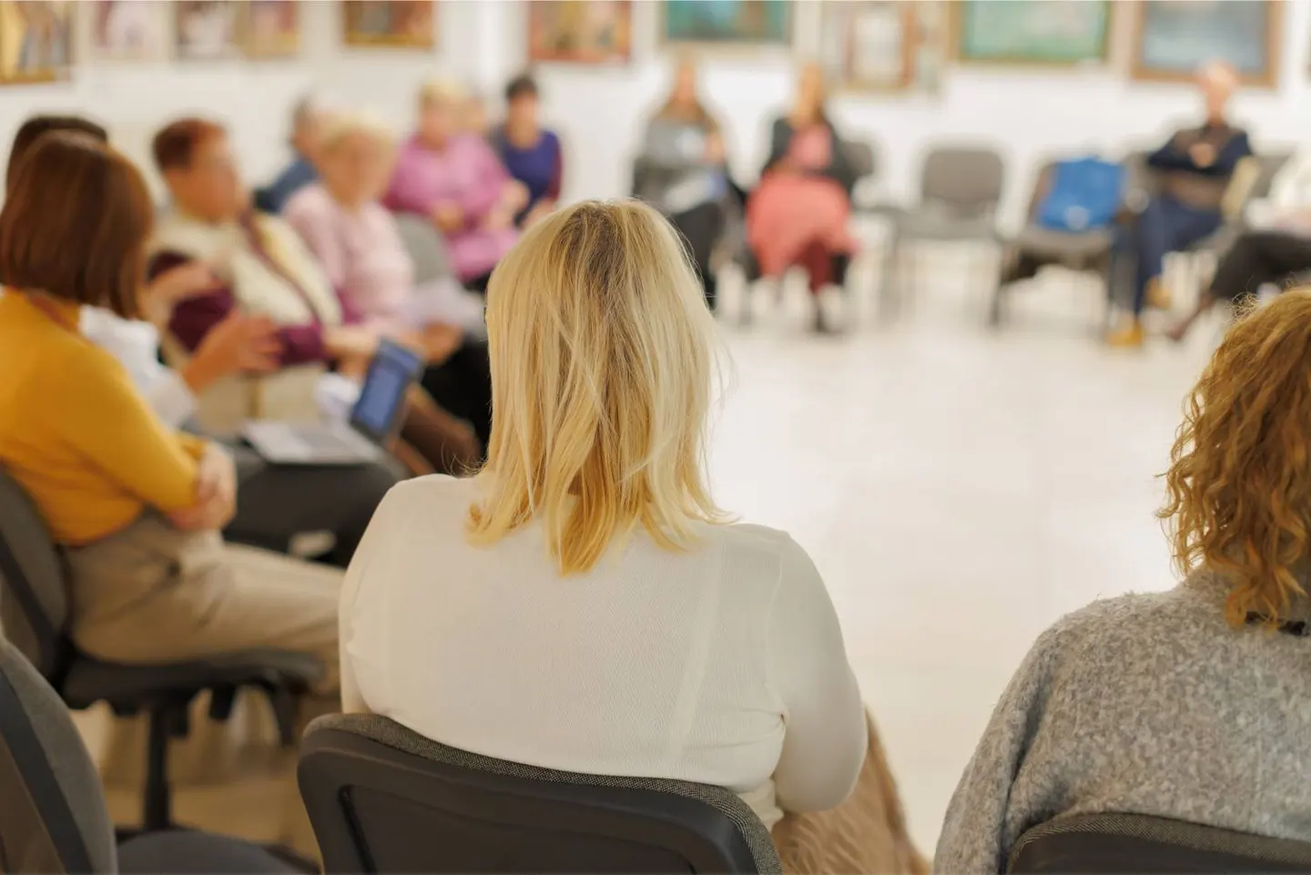 A group of people seated together in a classroom, listening to a speaker